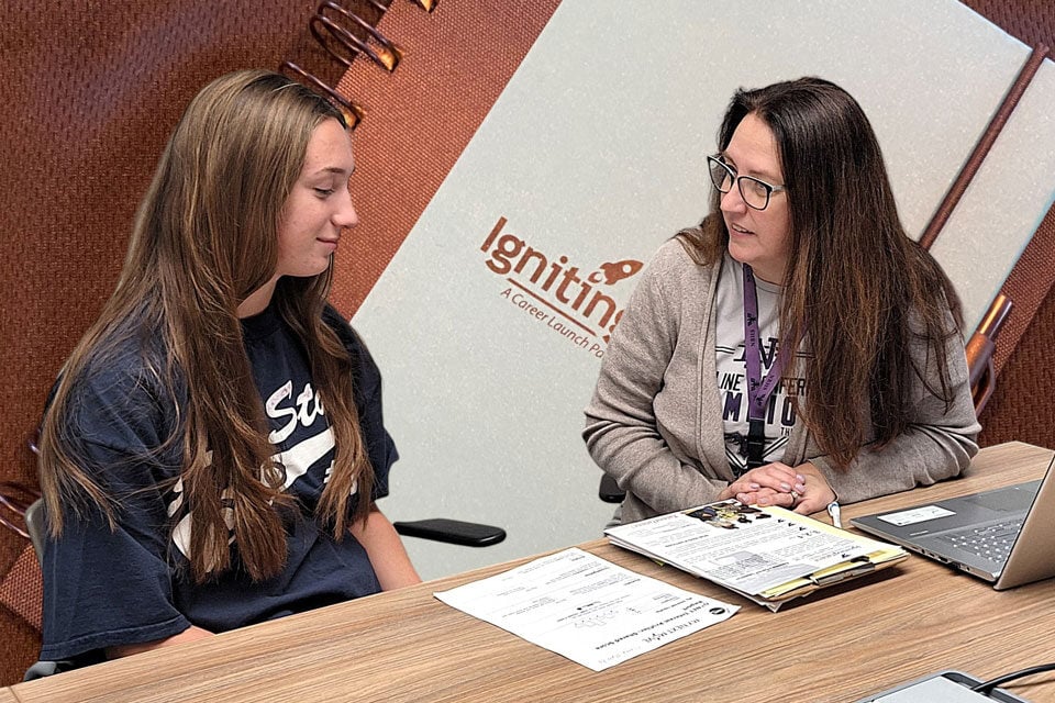 A student sitting next to a teacher.